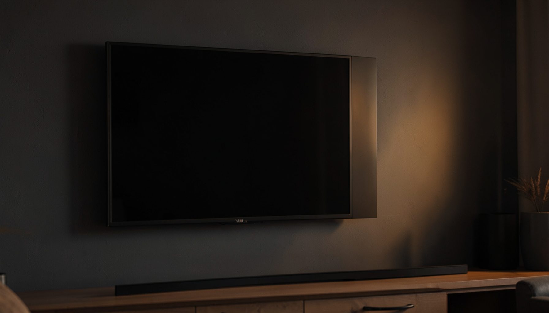 Close-up of a modern flat-screen television with a subtle warm glow on a dark living room wall, deep charcoal and soft amber tones creating a calm, focused mood